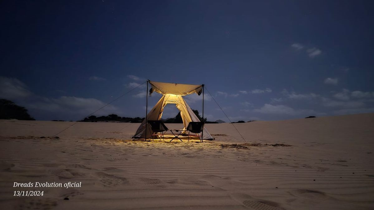 La tenda illuminata tra le dune al crepuscolo